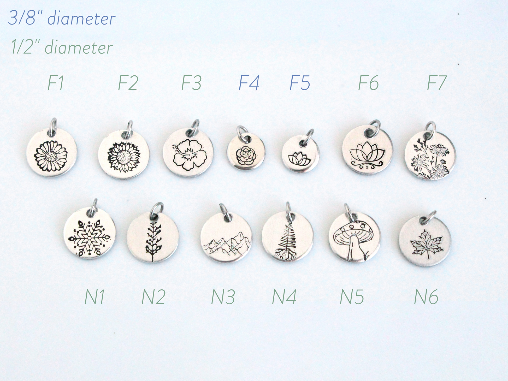 Collection of various silver pendants with different designs on a light blue background.