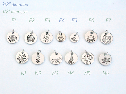Collection of various silver pendants with different designs on a light blue background.