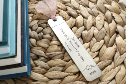 Hand stamped aluminum bookmark, 5" x 1", with text that reads, "Mrs. Nelson, Thank you for being part of my story. Love, Liam. 2024". The bookmark has a pale pink ribbon at the top.